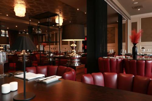 ein Restaurant mit roten Stühlen, einem Tisch und einer Bar in der Unterkunft Haverkamp Suites in Bremerhaven