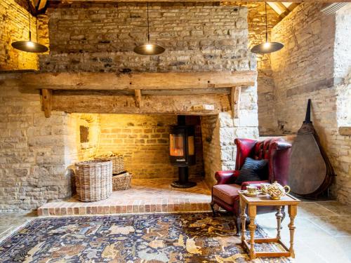 a living room with a stone fireplace and a chair at The Barns at Holy Well in Southam