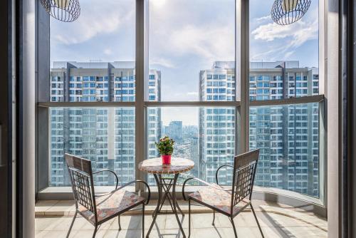 Isabelle Luxury Apartment inside Landmark 81 Tower في مدينة هوشي منه: طاولة وكراسي في غرفة مع نوافذ كبيرة