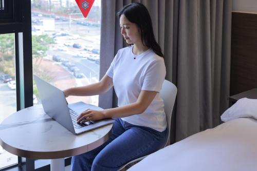 a woman sitting at a table with a laptop at From H Heritage Hotel in Mokpo