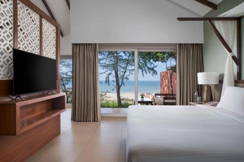 a bedroom with a bed and a television and a beach at Mandrem Beach Resort, a member of Radisson Individuals Retreat in Mandrem
