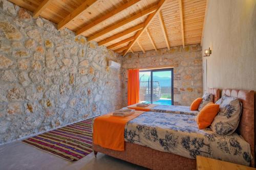 1 dormitorio con cama y pared de piedra en Villa İkizler 2, en Fethiye