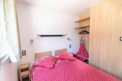 a bedroom with a pink bed with pink sheets at Mobilhome 3 étoiles - eeeada in Barjac