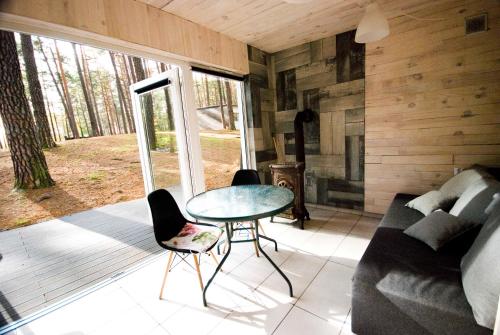 a living room with a table and chairs and a couch at Ośrodek La La Las - domki letniskowe w lesie nad jeziorem in Bytnica