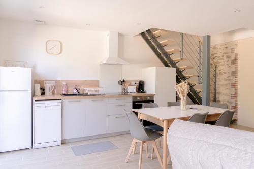 une cuisine avec des armoires blanches et une table avec des chaises dans l'établissement La Vie En Gîte (Le Scandinave), à Sainte-Florence