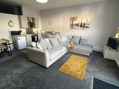 a living room with a white couch and a kitchen at The Print Room, 1 Bedroom Ground Floor Apartment in Carlisle