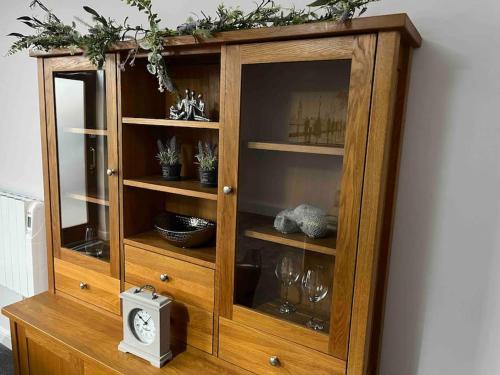a wooden cabinet with a clock and glasses in it at The Print Room, 1 Bedroom Ground Floor Apartment in Carlisle
