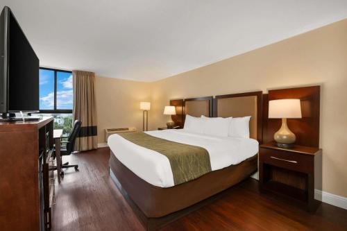 a hotel room with a bed and a flat screen tv at Comfort Inn Oceanside Deerfield Beach in Deerfield Beach