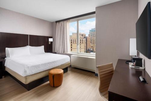 ein Hotelzimmer mit einem Bett, einem Schreibtisch und einem Fenster in der Unterkunft Hampton Inn Times Square Central in New York