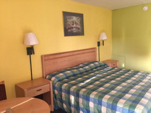 1 dormitorio con 1 cama, 2 lámparas y mesa en Statesman Inn en Terre Haute