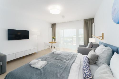 a bedroom with a large bed and a couch at Aquamarina Prima Deluxe Studios With Sea View by Renters in Międzyzdroje