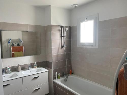 ein Badezimmer mit einem Waschbecken, einer Badewanne, einem Waschbecken und einem Spiegel in der Unterkunft Maison de 2 chambres avec jardin clos et wifi a Briscous in Briscous