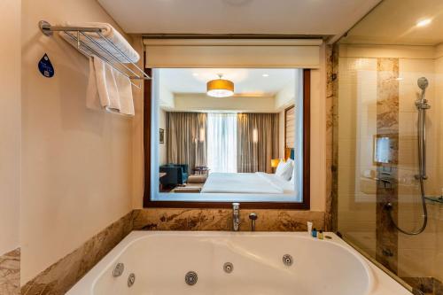 a bath tub in a bathroom with a large mirror at Radisson Blu Hotel, Indore in Indore