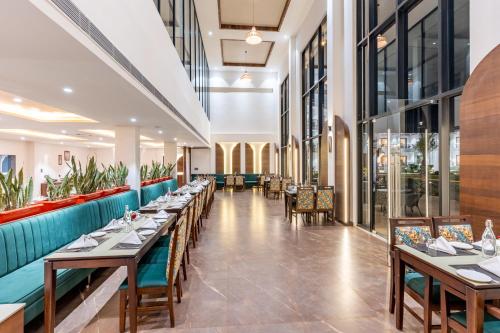 a dining room with tables and chairs and windows at Shervani Pebbles & Pines Resort & Spa, Corbett in Rāmnagar