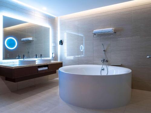 een grote badkamer met een bad en een wastafel bij Movenpick Hotel & Convention Centre KLIA in Sepang