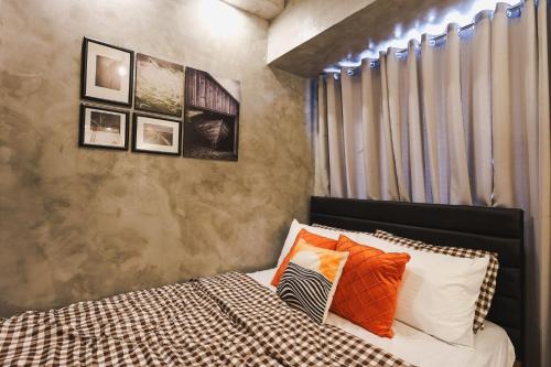 a bedroom with a bed with orange and white pillows at Kensal Industrial - Air Residences in Manila