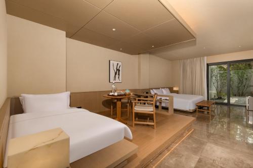 a hotel room with a bed and a table and chairs at Jiangnan House Chaozhou in Chaozhou