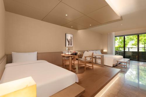 a bedroom with a bed and a table and chairs at Jiangnan House Chaozhou in Chaozhou