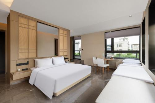 a bedroom with two beds and a table and chairs at Jiangnan House Chaozhou in Chaozhou
