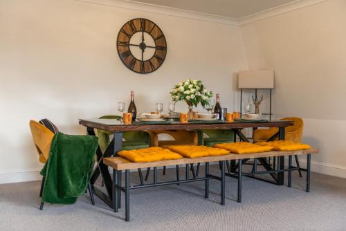 a dining room with a table and chairs with a clock on the wall at City Chic 3 Bedroom, 3 Bathroom Luxury Living 7 in London