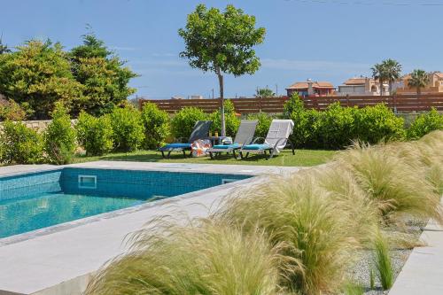 einen Pool in einem Garten mit zwei Gartenstühlen in der Unterkunft Villa Dianna by Estia in Gournes