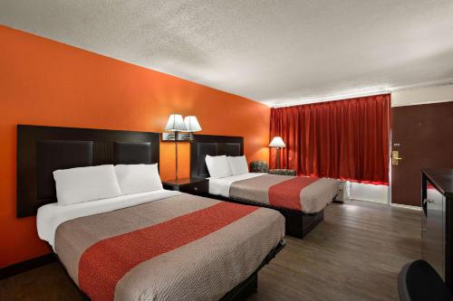 2 camas en una habitación de hotel con paredes de color naranja en Econo Lodge, en Yemassee