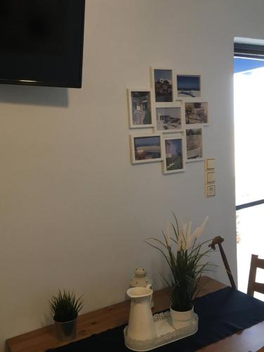 a dining room table with potted plants and pictures on the wall at Kea Houses View - Μαγευτική Θέα στο Αιγαίο Πέλαγος ΦΟΙΡΑ ΚΑΤΩ ΜΕΡΙΑ ΚΕΑΣ in Káto Meriá