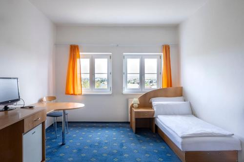 a room with a bed and a desk and a table at City inn Olomouc in Olomouc