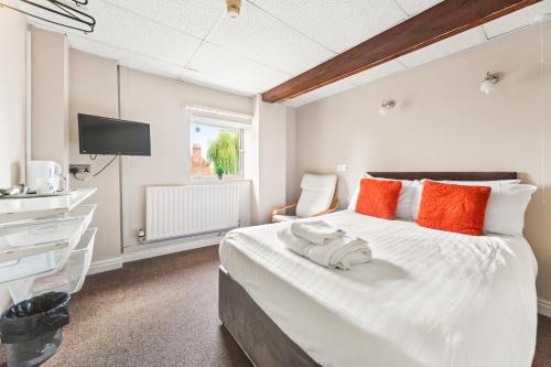a bedroom with a large white bed with orange pillows at Riverside Mews in Brigg