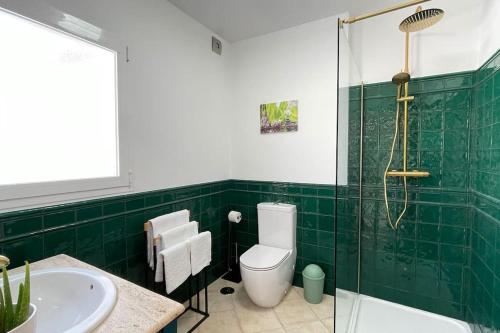 a green tiled bathroom with a toilet and a sink at Casa Azahar centrally located 2 bedroom apartment in Alhaurín el Grande