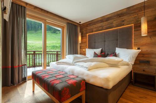 a bedroom with a large bed and a large window at Hotel Watles in Malles Venosta