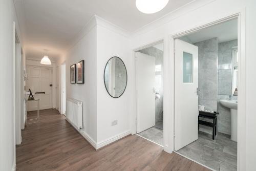 a white bathroom with a sink and a mirror at Luxe 3 Bedroom flat In London on Central Line for Families, Contractors, Business Travellers in Woodford Green