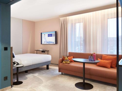 a hotel room with a bed and a couch at Novotel Hamburg Central Station in Hamburg