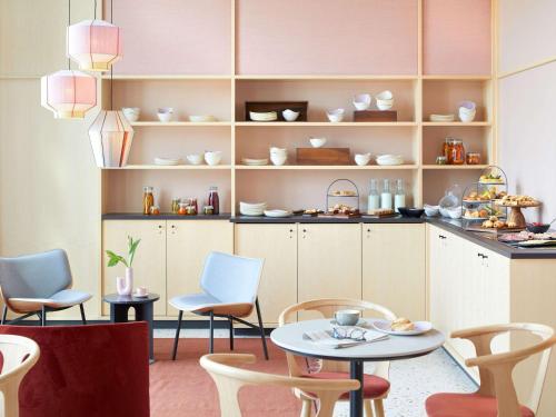a room with a table and chairs and shelves at Novotel Hamburg Central Station in Hamburg
