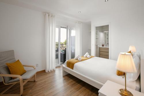 a white bedroom with a bed and a chair at Bela Vista in Atouguia da Baleia