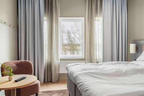 a bedroom with a bed and a table and a window at Aiden by Best Western Karlstad Arena in Karlstad
