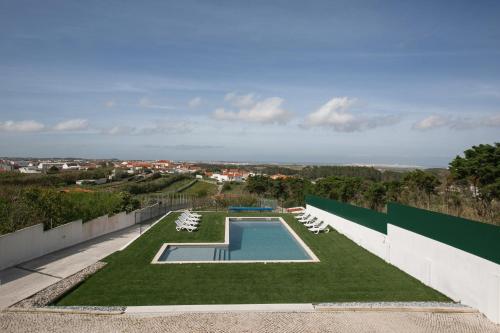 a swimming pool with lounge chairs and a lawn at Bela Vista in Atouguia da Baleia