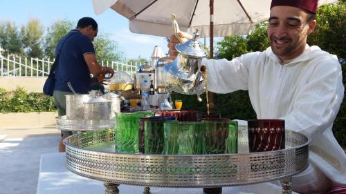 a man is pouring a drink into a drink at Hôtel Tamuda Beach in M'diq