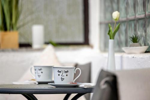 two coffee cups sitting on a table with a vase at Apartment Alb Glück 1 in Hechingen