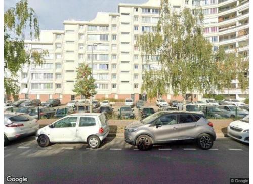 two cars parked in a parking lot in front of a large building at Chambre à Créteil in Créteil