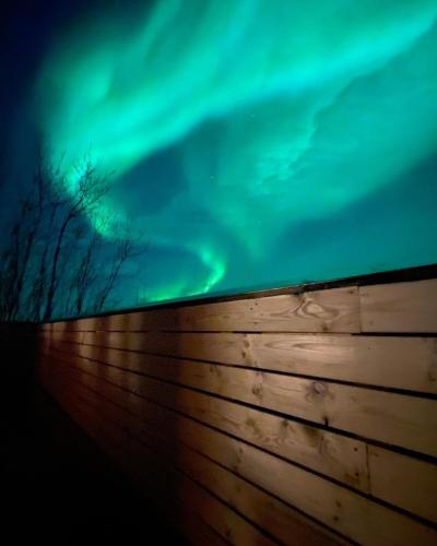 an aurora borealis over a wooden fence at Geysir Cabins - Golden Circle Cabin only 800m from Geysir in Selfoss