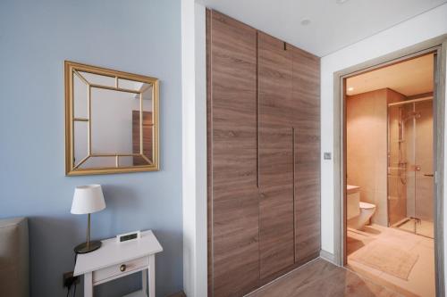 a bathroom with a wooden door and a mirror at Hububb Luxury Studio One Marina in Dubai
