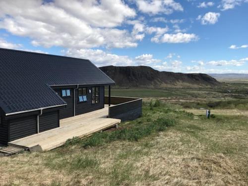 a black house with a wooden deck in a field at Geysir Cabins - Golden Circle Cabin only 800m from Geysir in Selfoss