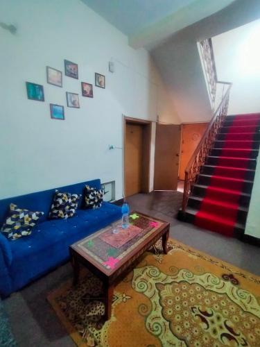 a living room with a blue couch and a table at Peridot Cottage in Islamabad