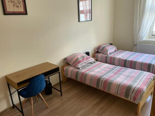 - une chambre avec deux lits, un bureau et une chaise dans l'établissement Apartamenty przy Starym Mieście, à Częstochowa