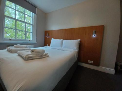 una camera da letto con un grande letto con asciugamani di B&B Belgravia a Londra