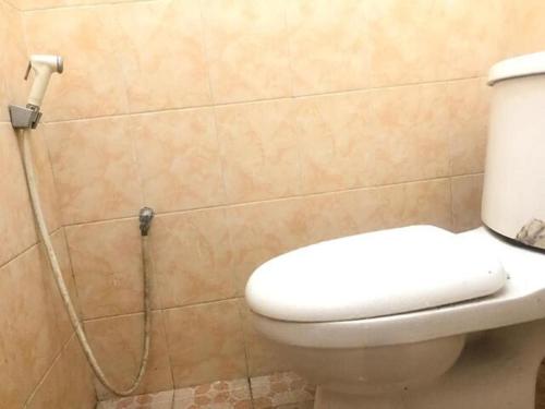 een badkamer met een toilet en een slang aan de muur bij OYO 93864 Wisma Gading Syariah in Pemalang