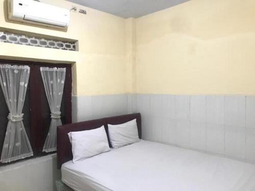 een kleine kamer met een bed en een raam bij OYO 93864 Wisma Gading Syariah in Pemalang