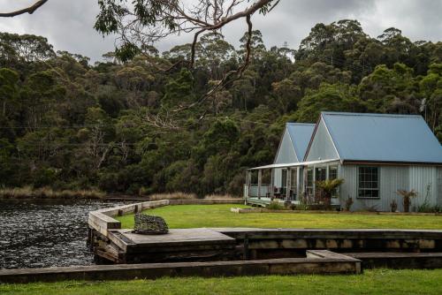 a house on a dock next to a body of water at Risby Cove Boutique Hotel in Strahan