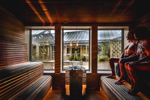 two people sitting on benches in a room with windows at Vadstena Klosterhotell Konferens & Spa in Vadstena